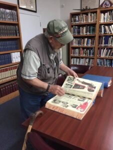 Man looking at book of newspapers