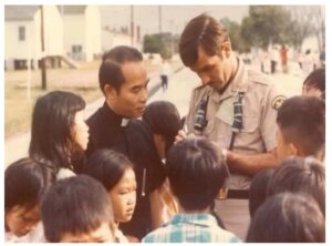 Ronald Hatcher, in his military uniform, speaking with a group of Vietnamese refugee children.
