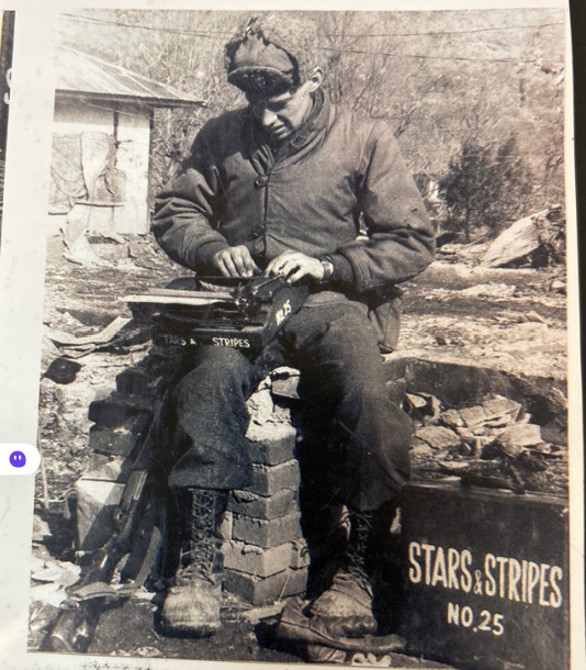 S/Sgt. Arthur "Mac" Millholland sits outdoors near Taegu, Korea, in 1951 with an M-1 rifle and a Stars and Stripes tywriter while working on a story.